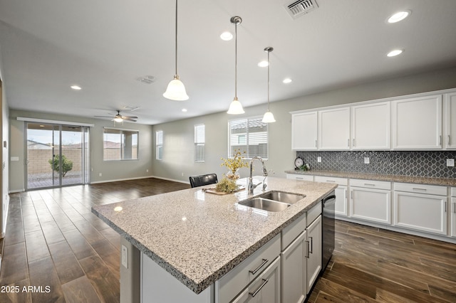 kitchen with hanging light fixtures, sink, a center island with sink, and white cabinets