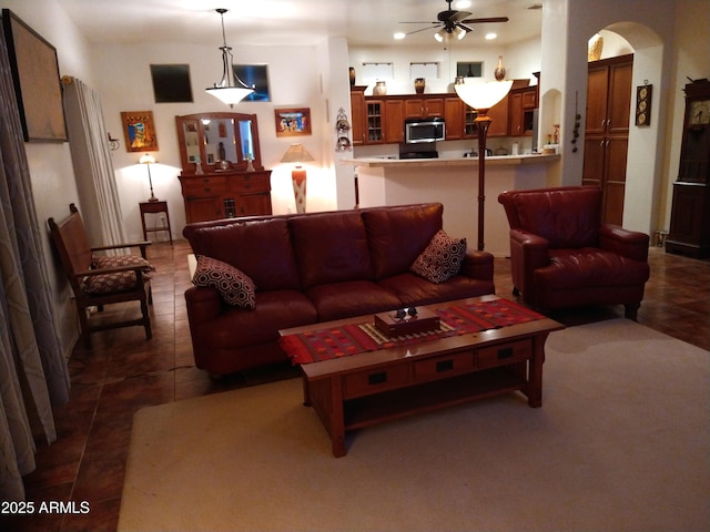 tiled living area with arched walkways and ceiling fan