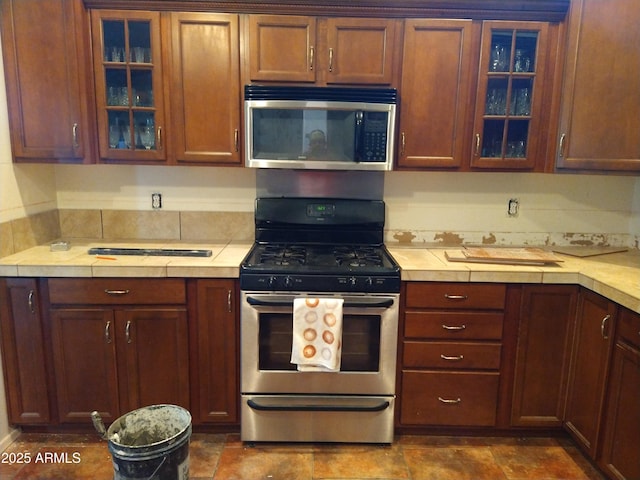 kitchen with stainless steel appliances, light countertops, and glass insert cabinets