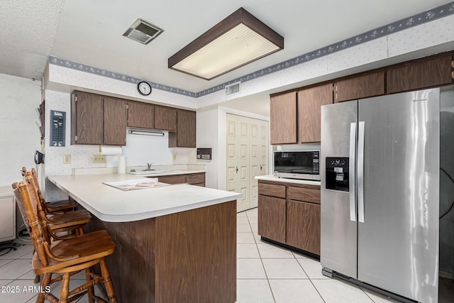 kitchen with light tile patterned floors, stainless steel appliances, kitchen peninsula, and a breakfast bar