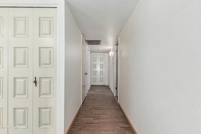 corridor featuring dark hardwood / wood-style floors and a textured ceiling