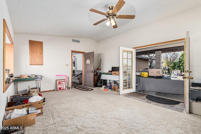 interior space with vaulted ceiling, carpet flooring, ceiling fan, and a textured ceiling