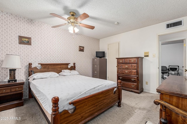 bedroom featuring ceiling fan, light carpet, and a textured ceiling