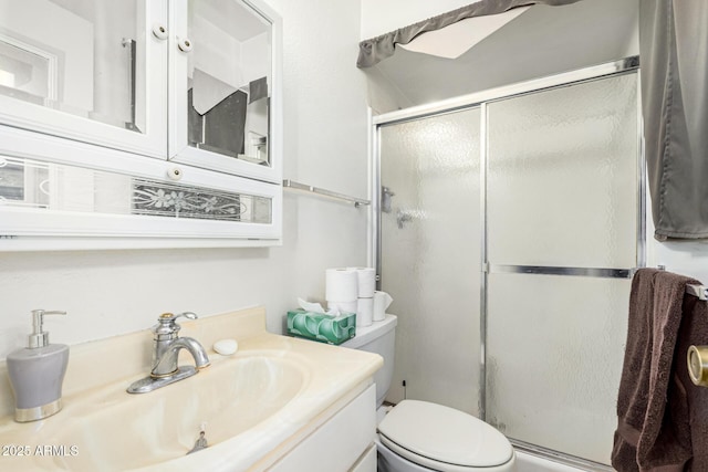 bathroom featuring vanity, a shower with shower door, and toilet