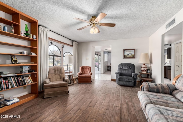 living room featuring ceiling fan, dark hardwood / wood-style floors, and a textured ceiling