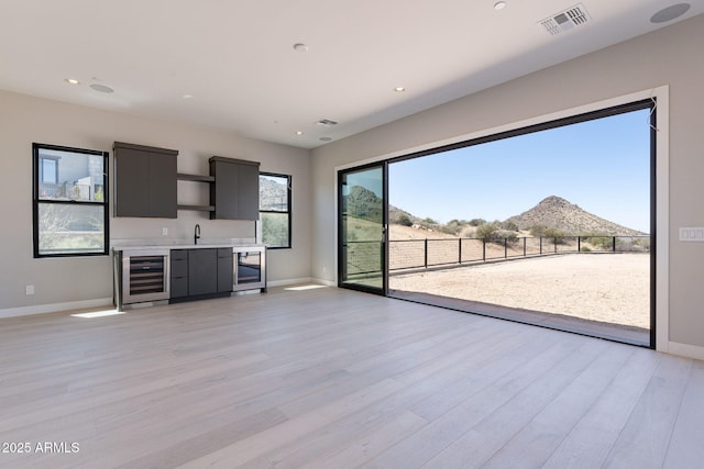23656 N 123rd St Unit 240, Scottsdale, AZ 85255 - unfurnished living room with light wood-style flooring, indoor wet bar, wine cooler, and visible vents