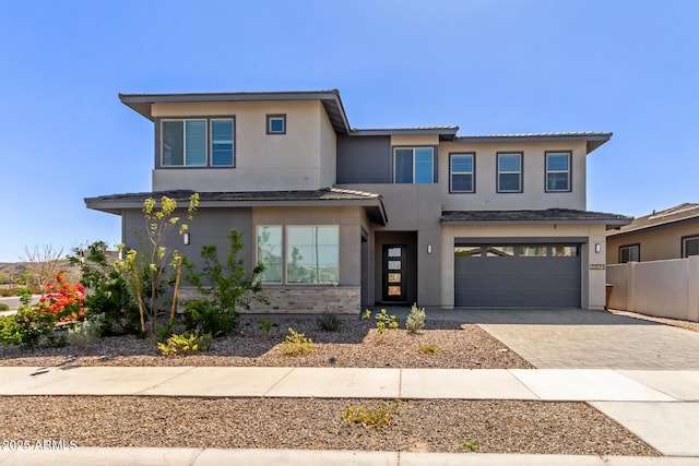 view of front facade featuring an attached garage, fence, driveway, and stucco siding