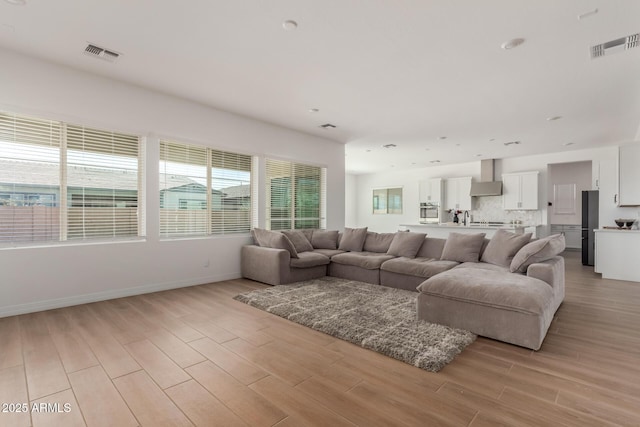 living room with baseboards, visible vents, and light wood finished floors