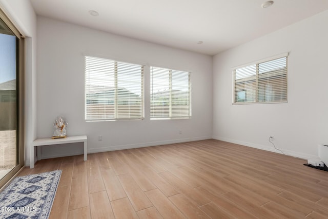 unfurnished room with baseboards, plenty of natural light, and light wood-style flooring