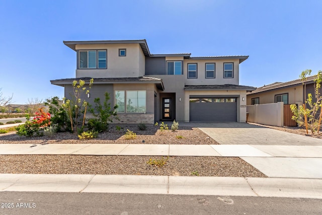 prairie-style house with fence, a tile roof, stucco siding, decorative driveway, and an attached garage