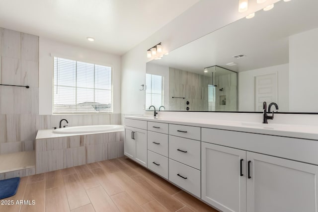 full bathroom with double vanity, a shower stall, wood finish floors, and a sink