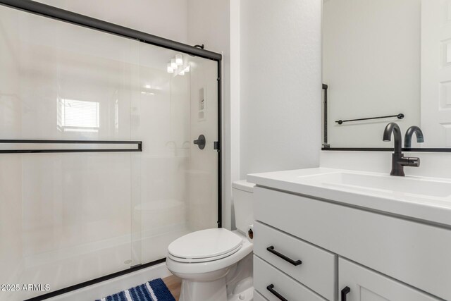 bathroom with vanity, a shower stall, and toilet