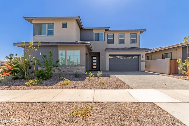 view of front of house featuring decorative driveway, fence, an attached garage, and stucco siding