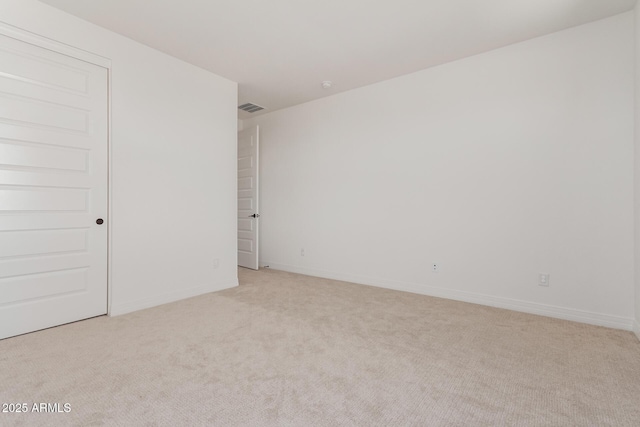 spare room featuring light carpet, visible vents, and baseboards