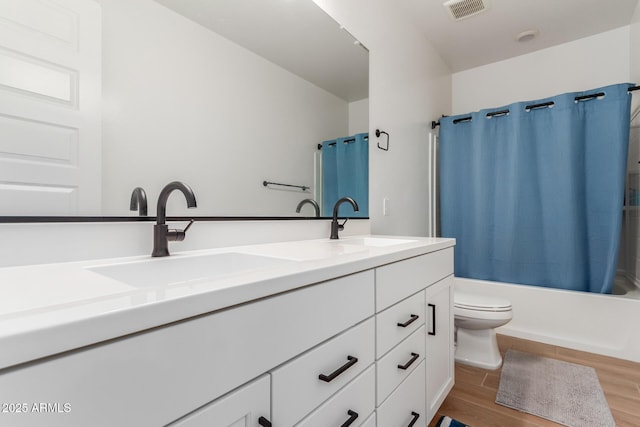 full bath with double vanity, visible vents, wood finished floors, and a sink