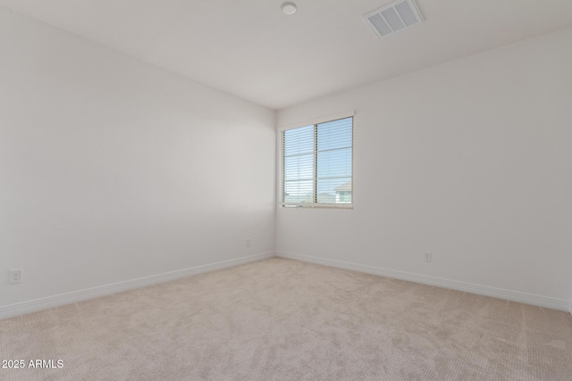 spare room featuring light carpet, visible vents, and baseboards