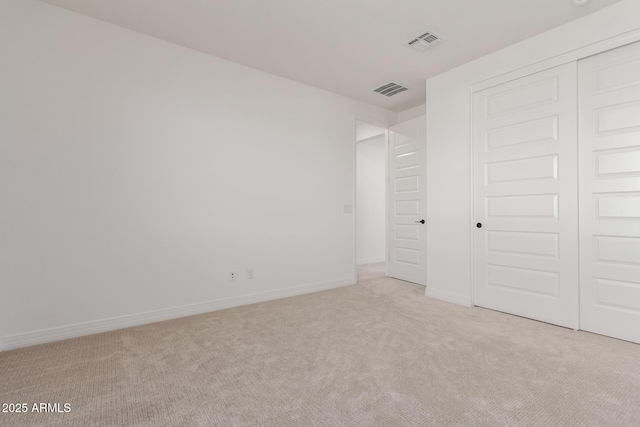 unfurnished bedroom featuring a closet, visible vents, light colored carpet, and baseboards