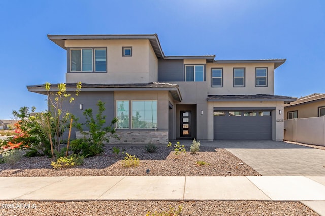 view of front of home featuring decorative driveway, fence, a garage, and stucco siding