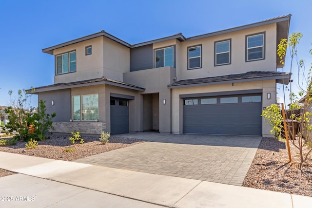 view of front of property with stucco siding, decorative driveway, and a garage