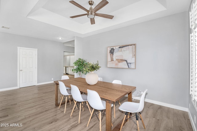 10809 W Harmony Ln, Peoria, AZ 85373 - dining space with visible vents, a raised ceiling, light wood-style floors, baseboards, and a ceiling fan