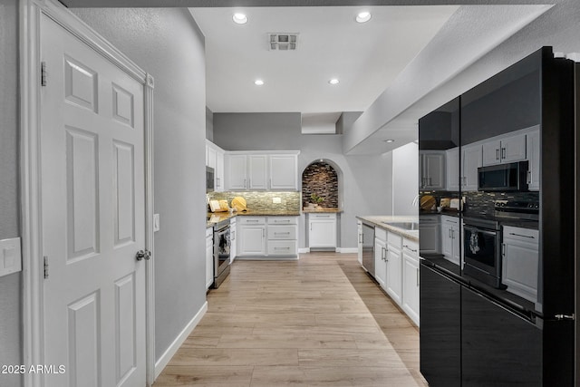 10809 W Harmony Ln, Peoria, AZ 85373 - kitchen featuring decorative backsplash, white cabinets, appliances with stainless steel finishes, visible vents, and light wood finished floors