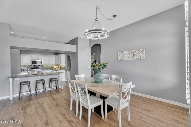 10809 W Harmony Ln, Peoria, AZ 85373 - dining space with recessed lighting, arched walkways, baseboards, light wood-type flooring, and a notable chandelier
