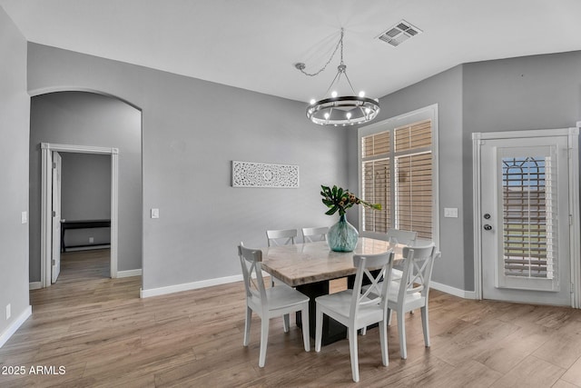 10809 W Harmony Ln, Peoria, AZ 85373 - dining space featuring light wood-style flooring, visible vents, baseboards, arched walkways, and a notable chandelier