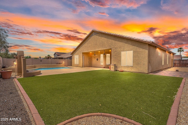 10809 W Harmony Ln, Peoria, AZ 85373 - back of property at dusk featuring a patio area, a fenced in pool, a fenced backyard, a lawn, and stucco siding