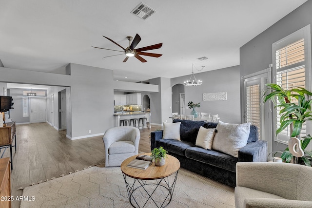 10809 W Harmony Ln, Peoria, AZ 85373 - living area with visible vents, light wood finished floors, arched walkways, and ceiling fan with notable chandelier