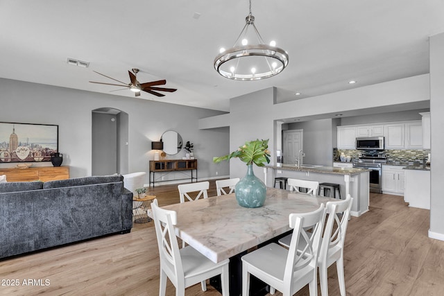 10809 W Harmony Ln, Peoria, AZ 85373 - dining room with ceiling fan with notable chandelier, arched walkways, visible vents, and light wood-style floors