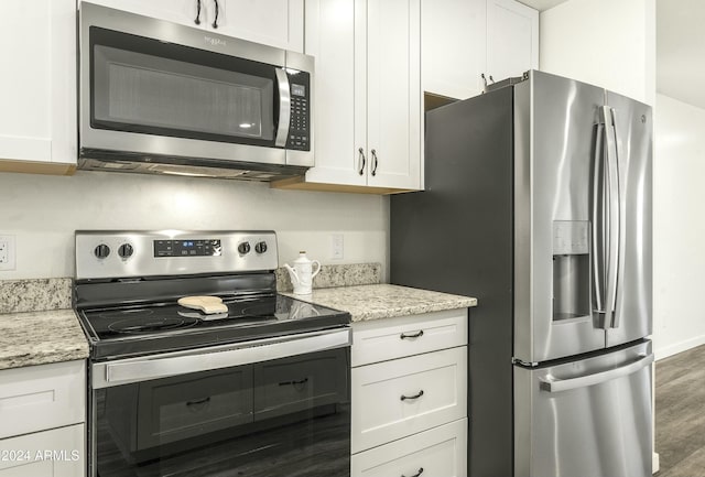 kitchen with light stone countertops, white cabinetry, stainless steel appliances, and dark wood-type flooring