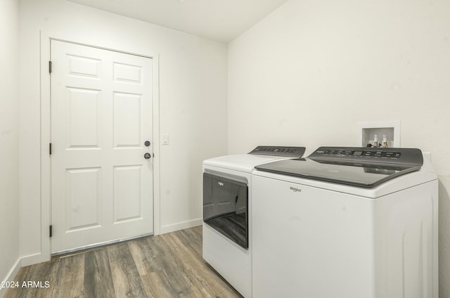 clothes washing area with hardwood / wood-style floors and washer and dryer