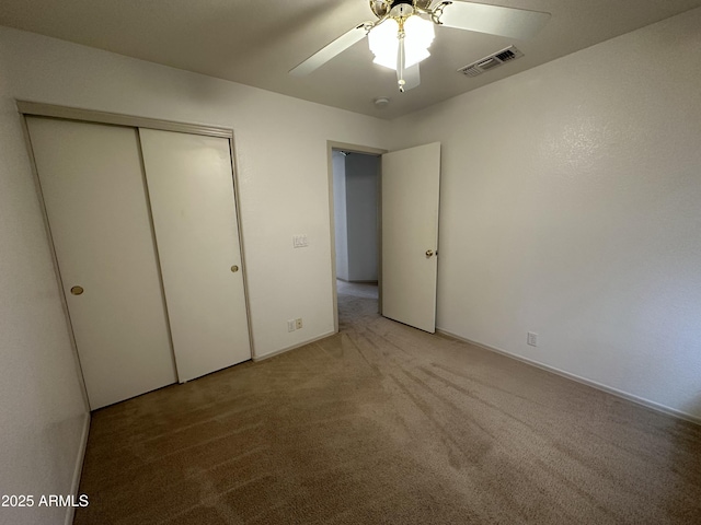 unfurnished bedroom featuring a ceiling fan, a closet, visible vents, and carpet flooring