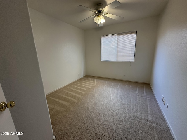 carpeted empty room with a ceiling fan and baseboards