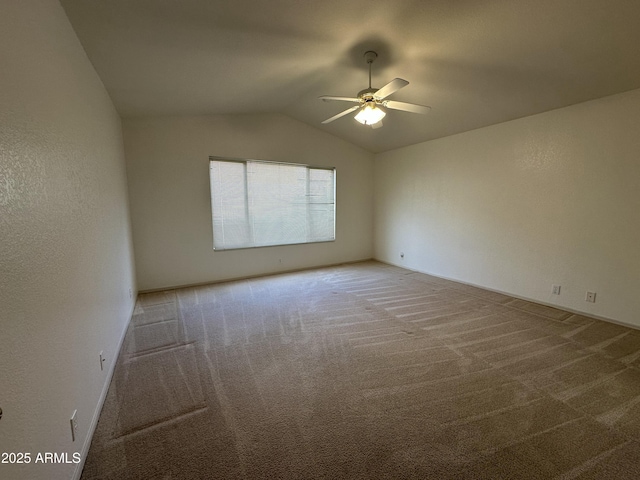 carpeted empty room with ceiling fan, vaulted ceiling, and a textured wall