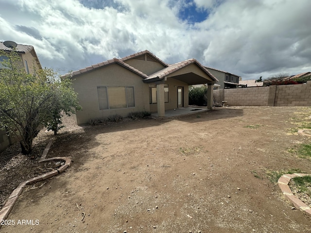 back of property with a fenced backyard, a tiled roof, a patio, and stucco siding