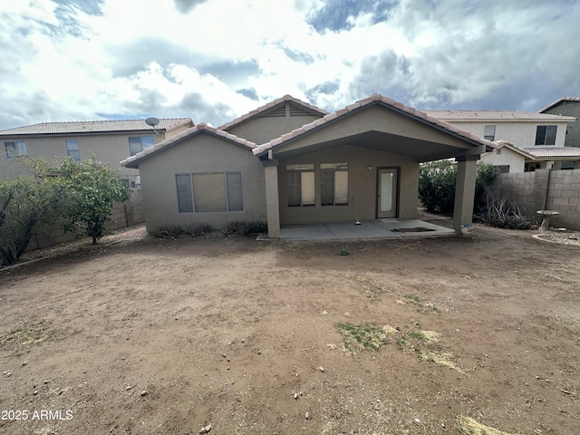 rear view of property with a tiled roof, a patio area, a fenced backyard, and stucco siding