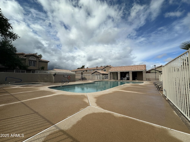 community pool featuring an outbuilding, a patio area, and fence