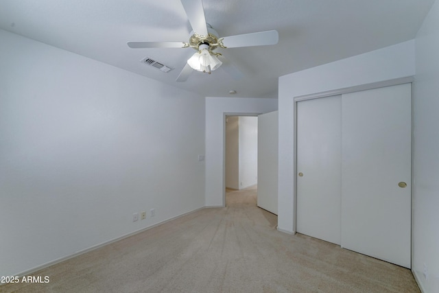 unfurnished bedroom featuring light carpet, ceiling fan, a closet, and visible vents