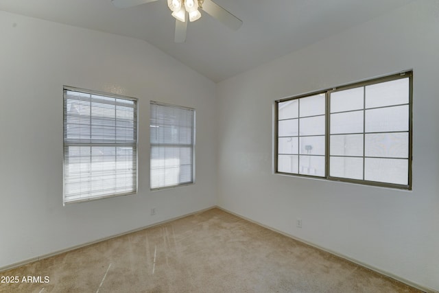 empty room with a healthy amount of sunlight, a ceiling fan, vaulted ceiling, and carpet flooring