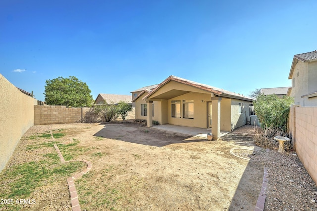 back of property featuring a fenced backyard, central AC, a tile roof, stucco siding, and a patio area