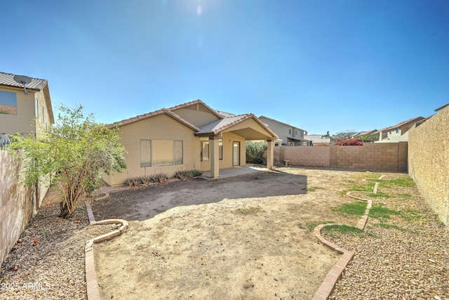 rear view of property with a patio area, a fenced backyard, a tiled roof, and stucco siding