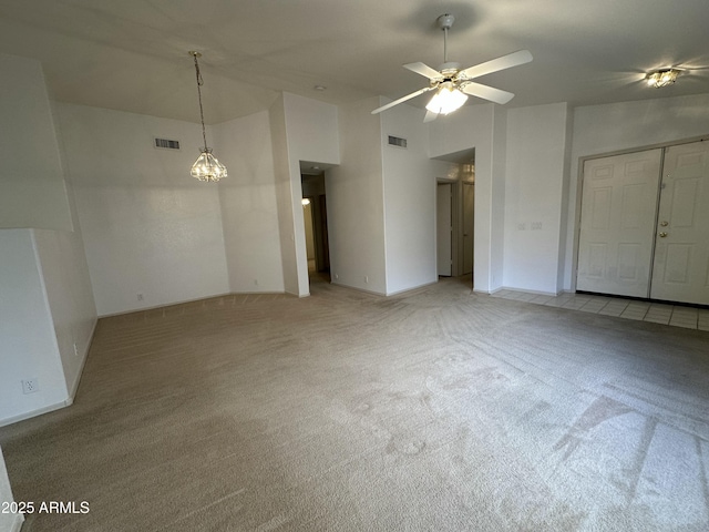 empty room with light carpet, a high ceiling, visible vents, and a ceiling fan