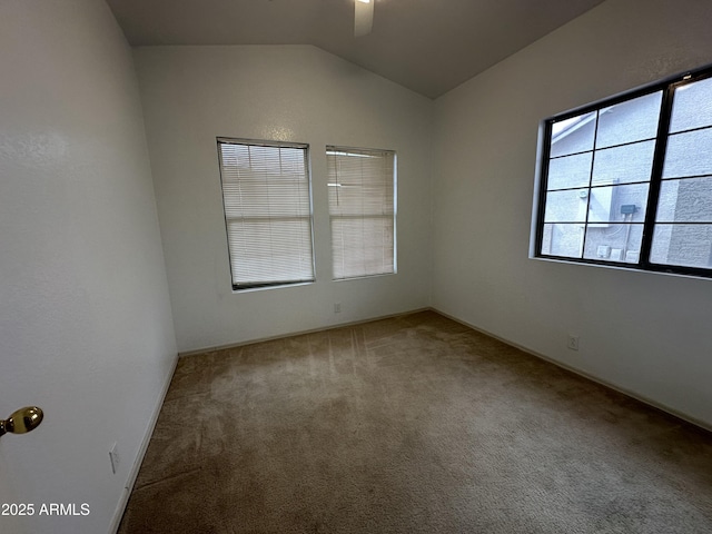 carpeted spare room with vaulted ceiling and a ceiling fan