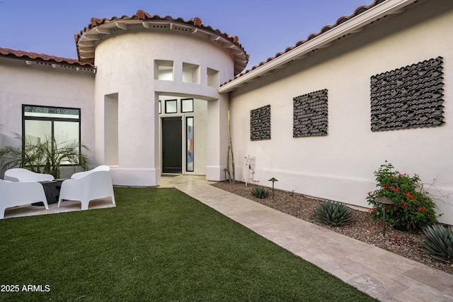 rear view of house featuring a lawn and stucco siding