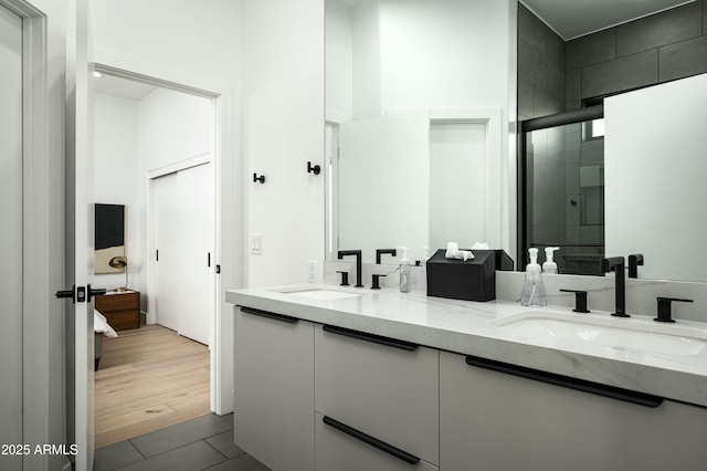 bathroom with double vanity, tile patterned flooring, a shower stall, and a sink