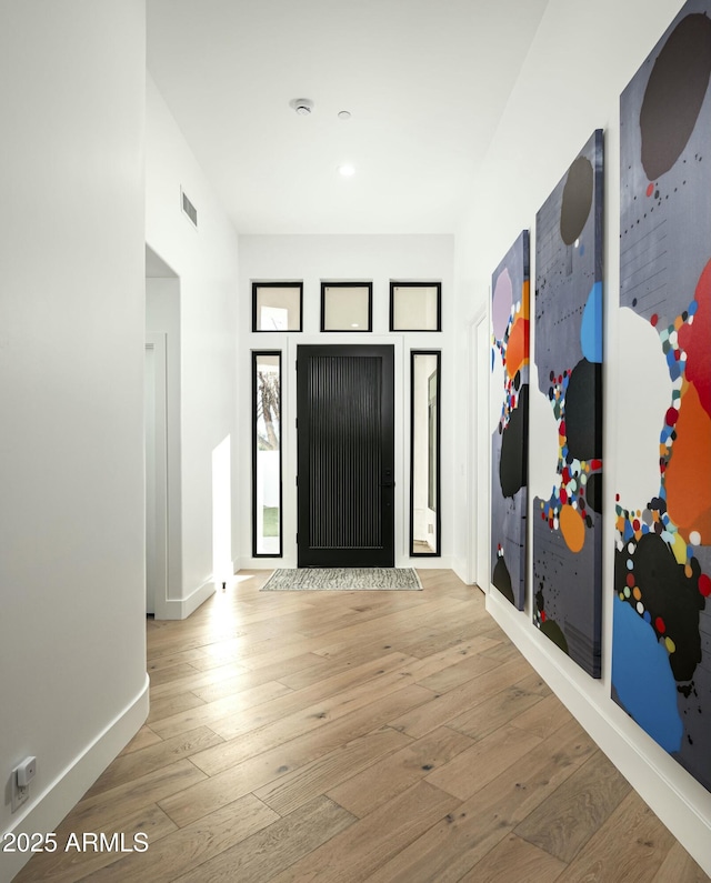 entrance foyer with wood-type flooring, visible vents, and baseboards