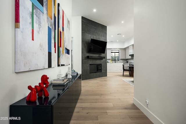 hall with light wood-style floors, recessed lighting, and baseboards