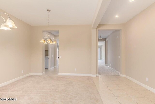 carpeted empty room featuring washer / dryer and a chandelier