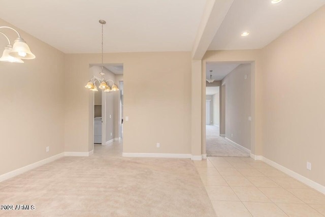 unfurnished room with light colored carpet, light tile patterned flooring, a notable chandelier, and baseboards